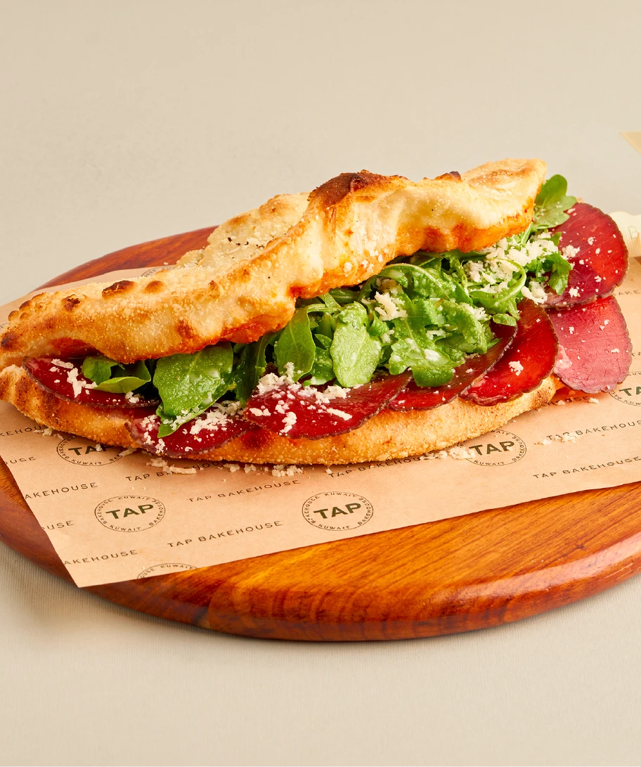 Fresh TAP Bakery sandwich on a wooden board